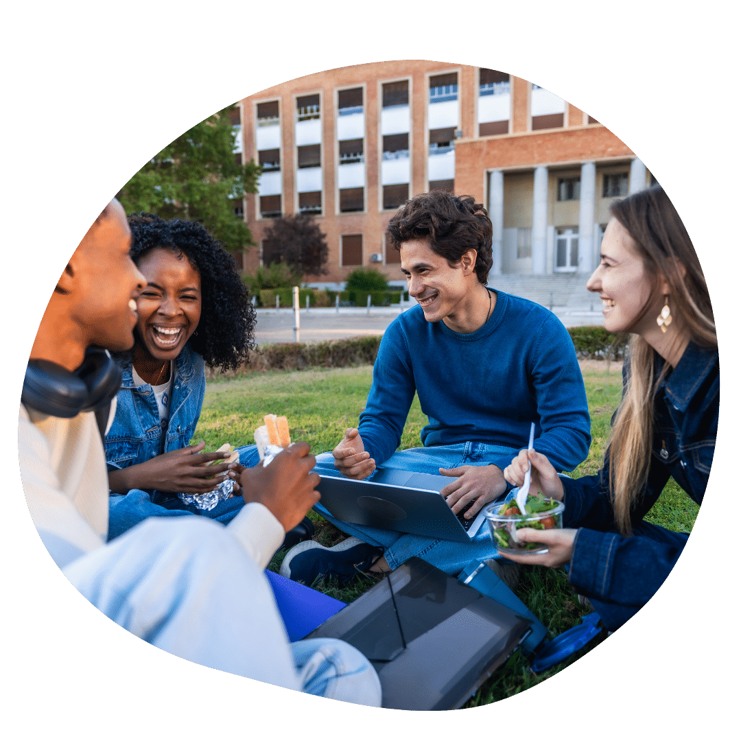 College students smiling and laughing while sitting on the campus lawn