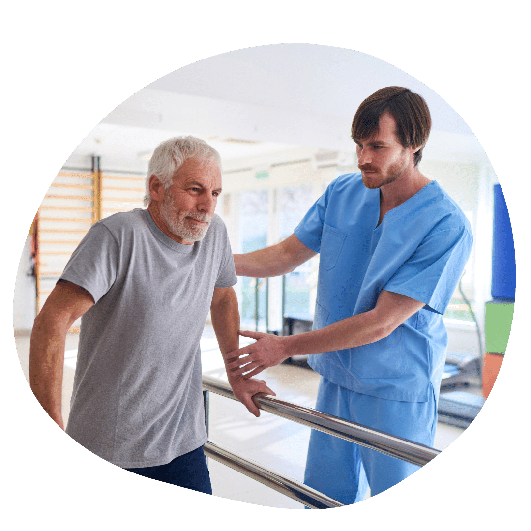 A physical therapist in blue scrubs helping his patient regain strength to walk